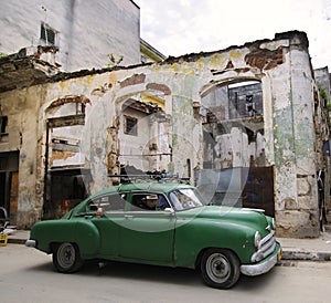 Green car on eroded havana street, cuba