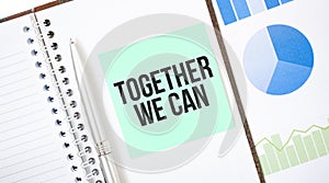 Green card on the white notepad. Text Together We Can. Business concept