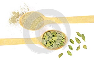 Green cardamom seeds and powder in a wooden spoon isolated on white background. Top view. lay flat