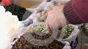 Green cardamom seeds and sellers hand at market counter.