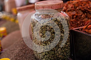 Green cardamom spice grains collected in glass jar sold in Goa market in India. Small spicy-sweet pods of piquancy. photo