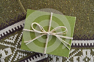 Green cardboard gift box on knitted woolen background