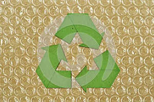 Green cardboard recycling symbol on plastic bubble wrap - Concept of paper and plastic recycling