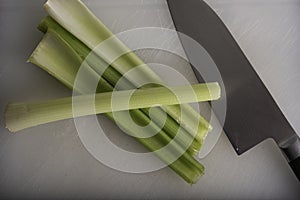 Green Celery Being Sliced on White Cutting Board