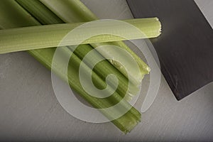 Green Celery Being Sliced on White Cutting Board