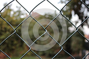 Green chain link fence up close blurred background