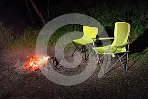 Green chairs near bonfire at night
