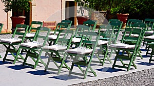 Green chairs are set up in rows for an event