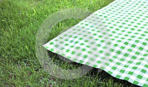 Green checkered cloth on grass empty space advertisement design. Food promotion. Picnic towel flat lay