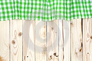 Green checkered tablecloth on wooden table, top view