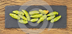 Green cheiro peppers on a stone board over wooden table. Typical brazilian ingredient photo