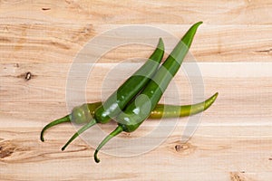 Green chili peppers on wooden table.
