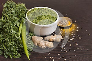 Green chili thecha or chutney with ingredients served in a bowl