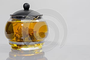 Green Chinese tea flower bud blooming in glass teapot. on white background