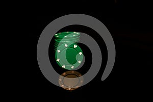 Green chips stack with a green chip in front isolated on black with reflection