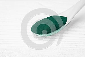 Green chlorella and spirulina powder in ceramic spoon, from above view, selective focus