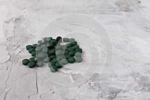 Green chlorella tablets on gray concrete background. Chlorella is a single-celled green algae, it is used to make nutritional supp photo
