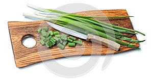 Green chopped scallions and kitchen knife on vintage wooden chopping board with life eddge isolated