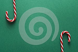 Green Christmas background with red candy canes. Copy space. Christmas minimalism.