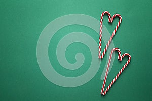 Green Christmas background with red candy canes. Copy space. Christmas minimalism.
