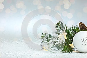 Green christmas tree branch, decorative glass balls and garland lights on white background