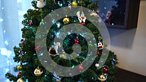 Green Christmas tree decorated with colorful toys and luminous garlands in the room