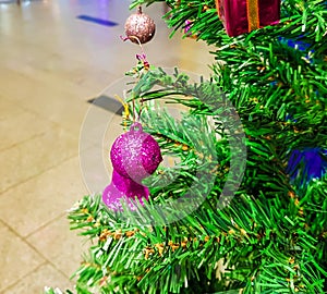 Green christmas tree decorated with colurful balls bells and gift boxes