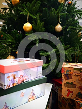 Green Christmas tree with golden balls.  Gift boxes under the tree