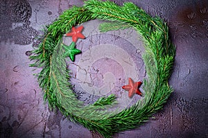 Green Christmas wreath with stars decorations on dark background.