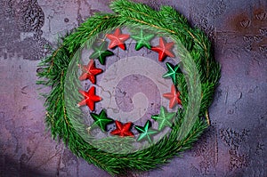 Green Christmas wreath with stars decorations on dark background.