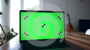 Green chromakey screen of modern laptop on wooden table