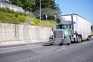 Green classic big rig semi truck with tall pipes and heavy duty