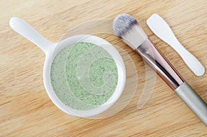 Green clay mask in a small white bowl. Diy facial or hair mask, body wrap recipe. Natural beauty treatment and spa.