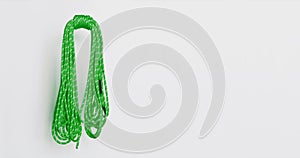 Green climbing rope coil sways slowly, isolated on white background, with space for text