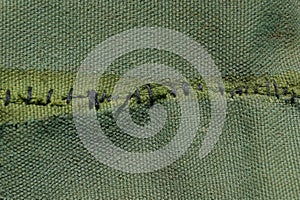 Green cloth texture with black stitching on the fabric