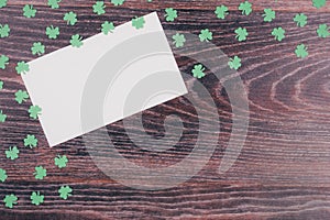 Green clover leaves and card on a wooden background.