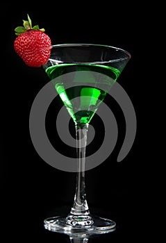 Green cocktail absinth decorated with red strawberry in martini