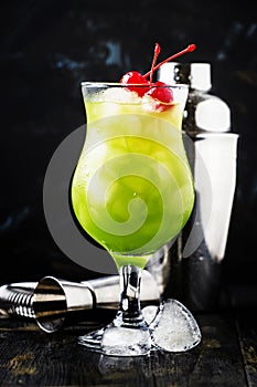 Green cocktail with maraschino cherries in a hurricane glass, da