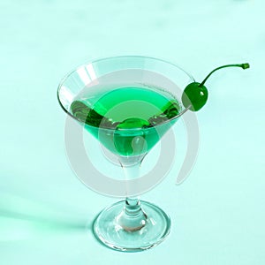 Green cocktail with maraschino cherry in martini glass