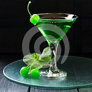 Green cocktail with maraschino cherry in a martini glass