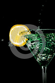 Green cocktail water drink splash in the glass with lemon Isolated on black