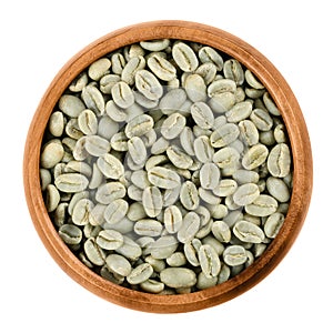 Green coffee beans in a wooden bowl over white