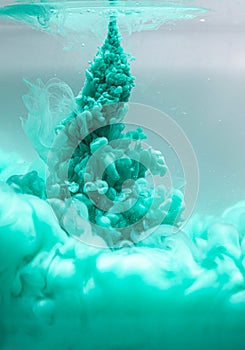 Green color drop in water, photo in motion. Ink swirling in fluid