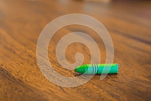 Green color pastel crayon on brown wooden table