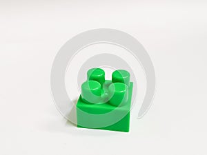 Green color plastic building block against white background. Education and development concept.
