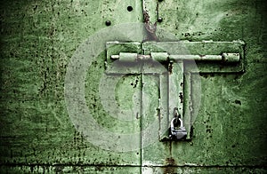 Green color rusty door close up detail with padlock and bolt