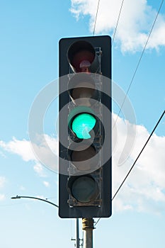 Green color on the traffic light with cloudy sky on the background