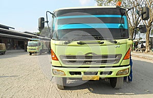Green colored flatbed heavy trucks used to transport and distribute cements sacks from factory to points of sales or distributors