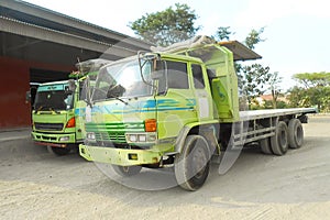 Green colored flatbed heavy trucks used to transport and distribute cements sacks from factory to points of sales or distributors