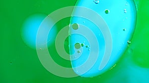 Green colored water surface with clear oil droplets mixing together, abstract wallpaper background.